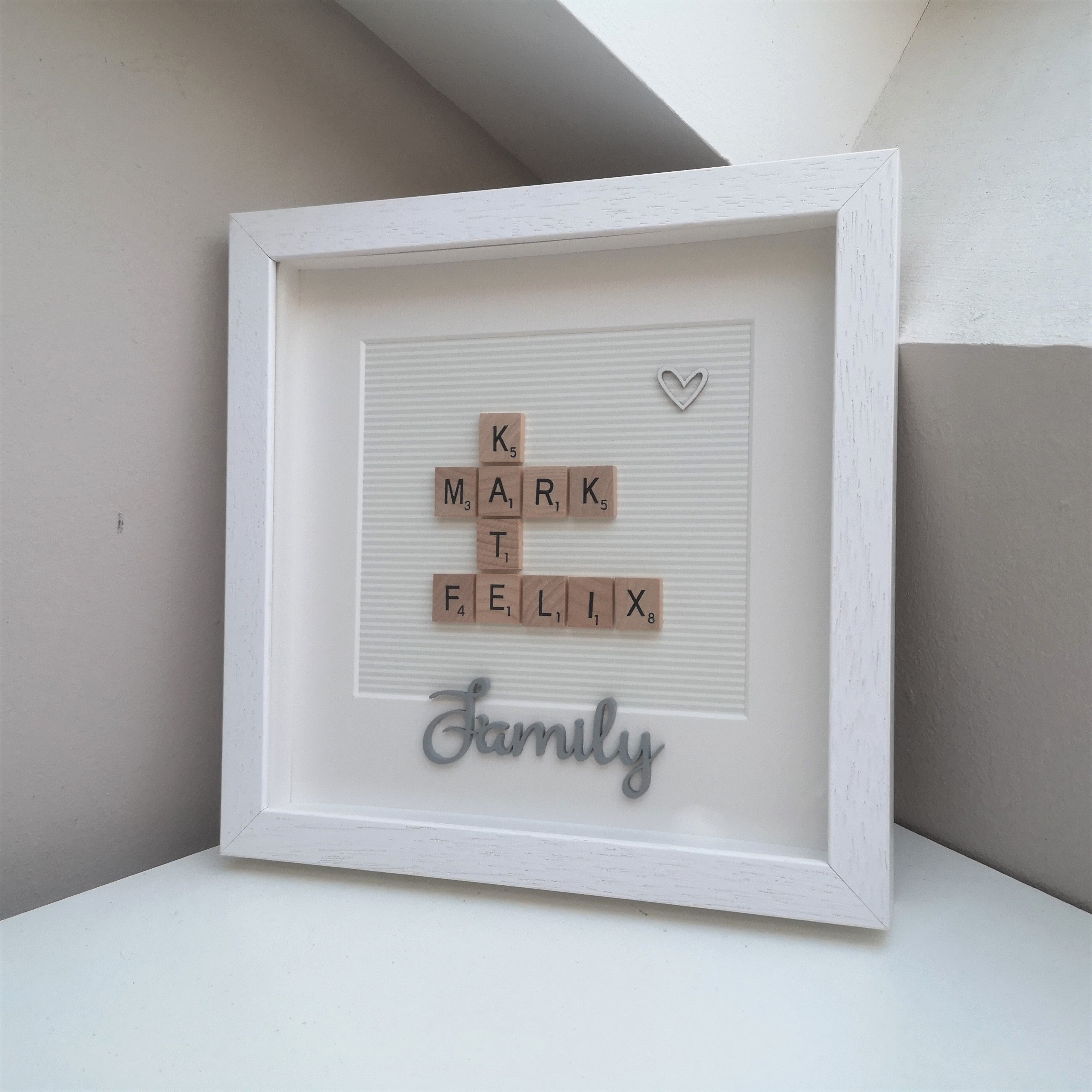 Family Names in wooden scrabble tiles on grey pinstripe background with wooden FAMILY embellishment in a handmade white 25x25cm deep box wooden frame