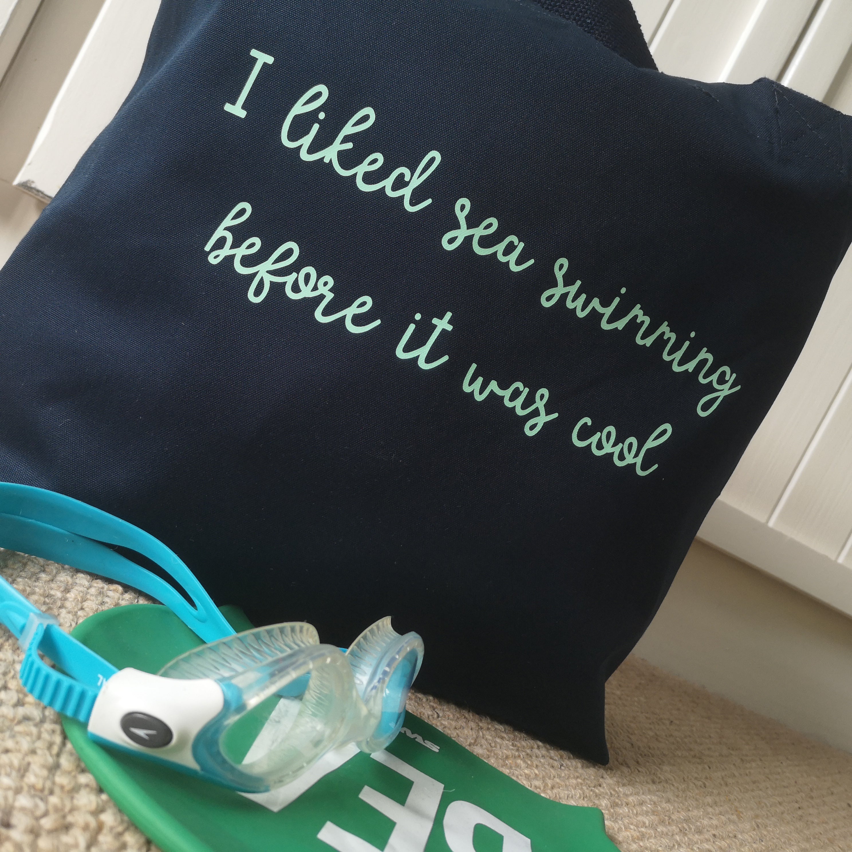 A navy organic cotton tote with the following slogan in mint green on it - I liked sea swimming before it was cool