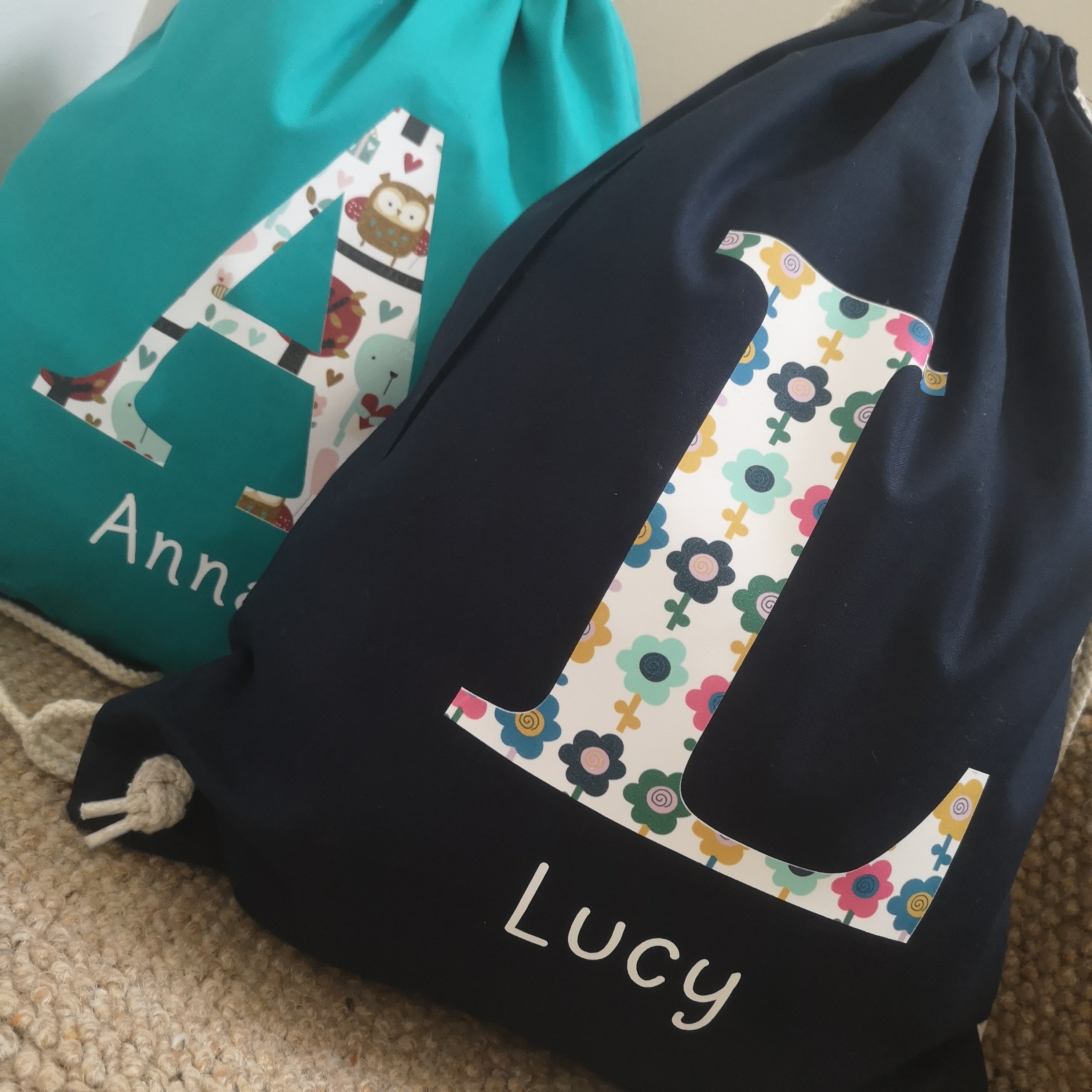 3 of my personalised patterned Initial drawstring bags.  The bags come in french navy, pink, emerald green and soft grey.  the name appears in white below the initial and there is a choice of patterns for the initial.