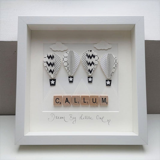 4 black & white patterned papercut balloons on a white mountain background in a handmade 25x25cm deep box wooden frame.
