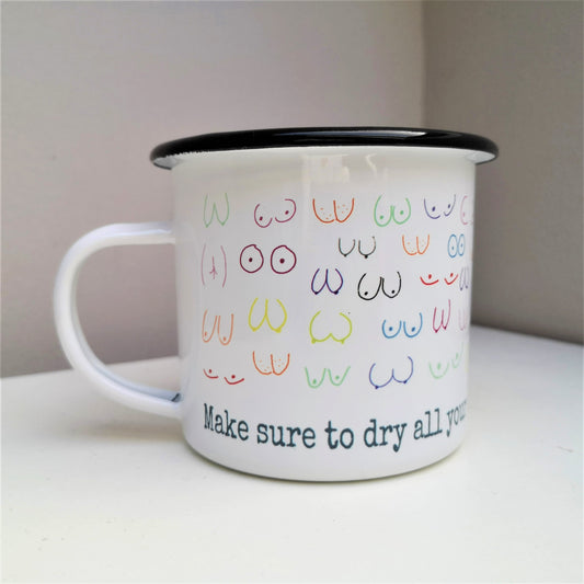A White enamel mug with a black rim with the following design wrapped around the mug  - MAKE SURE TO DRY YOUR WOBBLY BITS AND DON'T FORGET YOUR PANTS and above the text lots of different coloured hand drawn boobs and bums