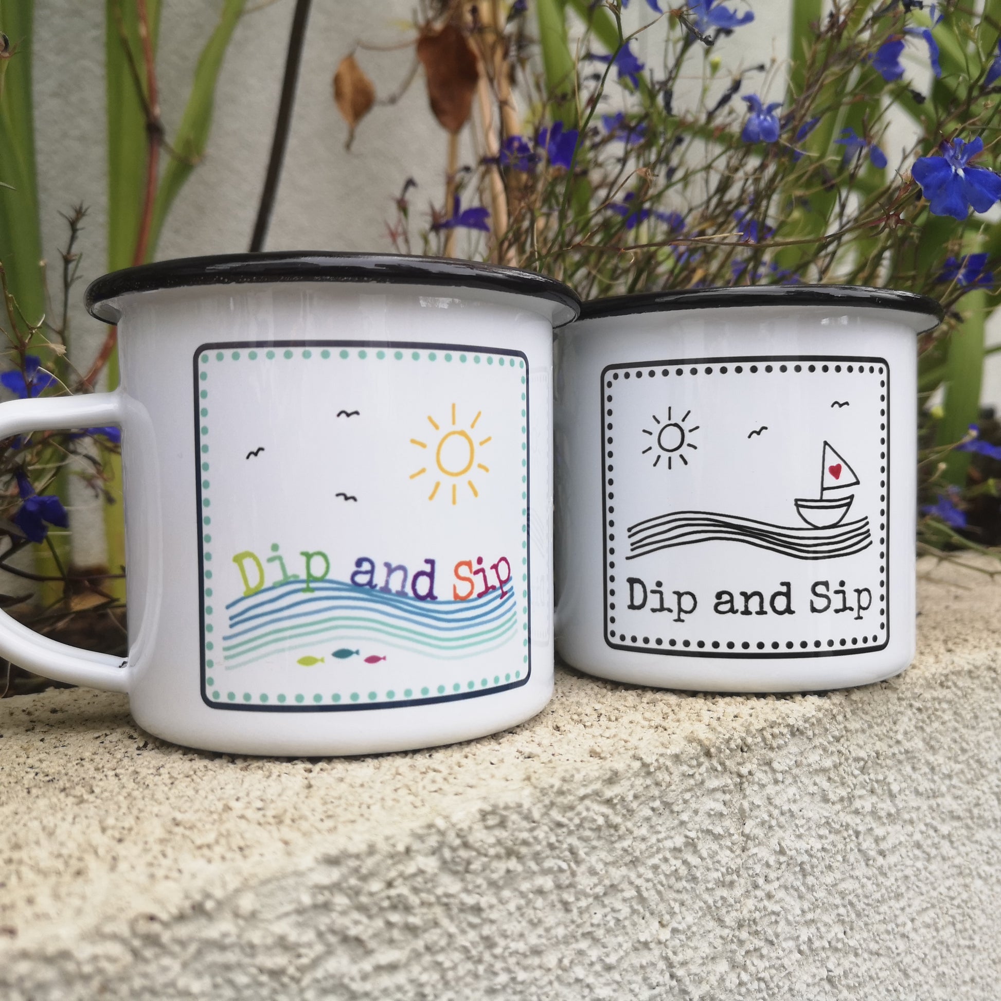 A white steel enamel mug with a year round swimmer's mantra on it - dip and sip.  Photo shows both designs available - 1 in black and white with a sailboat, the other with coloured fish under the waves