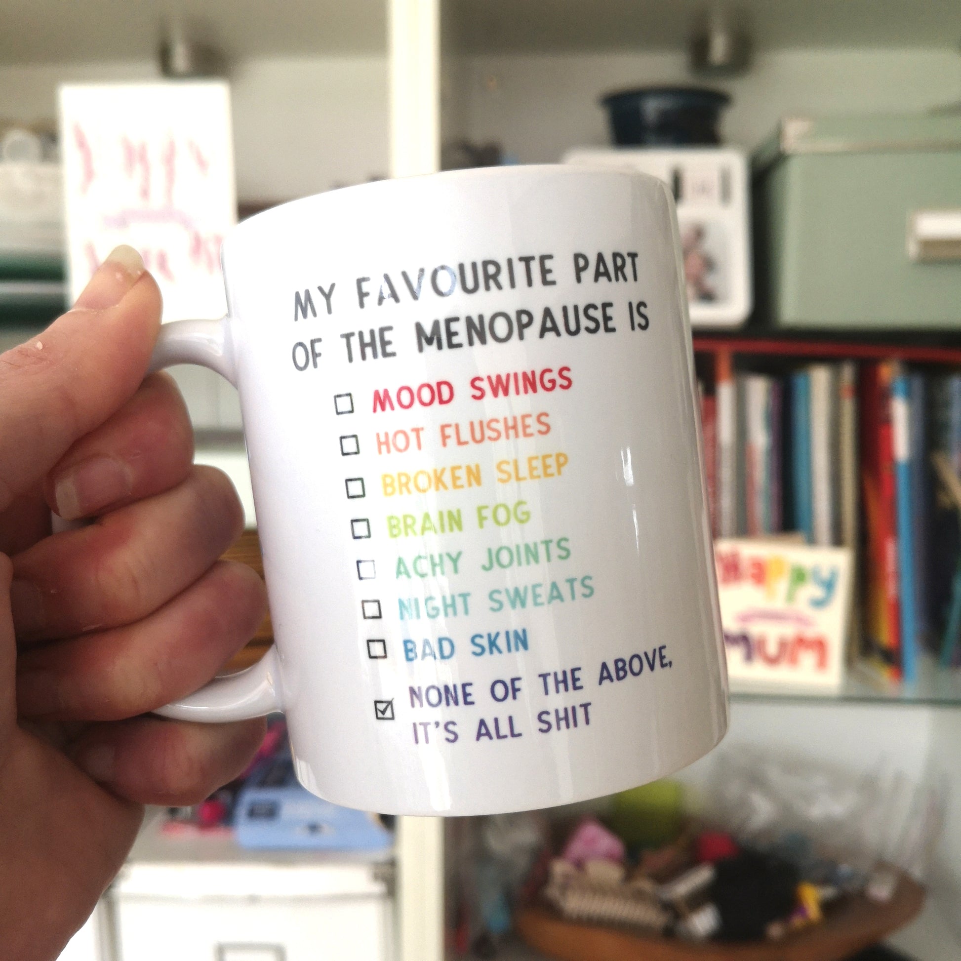 A white ceramic mug with 'My favourite part of the menopause is...' and a list of some of its wonderful symptoms.  Obviously the one ticked is 'None of the above. It's all shit', as it is all fairly shit!