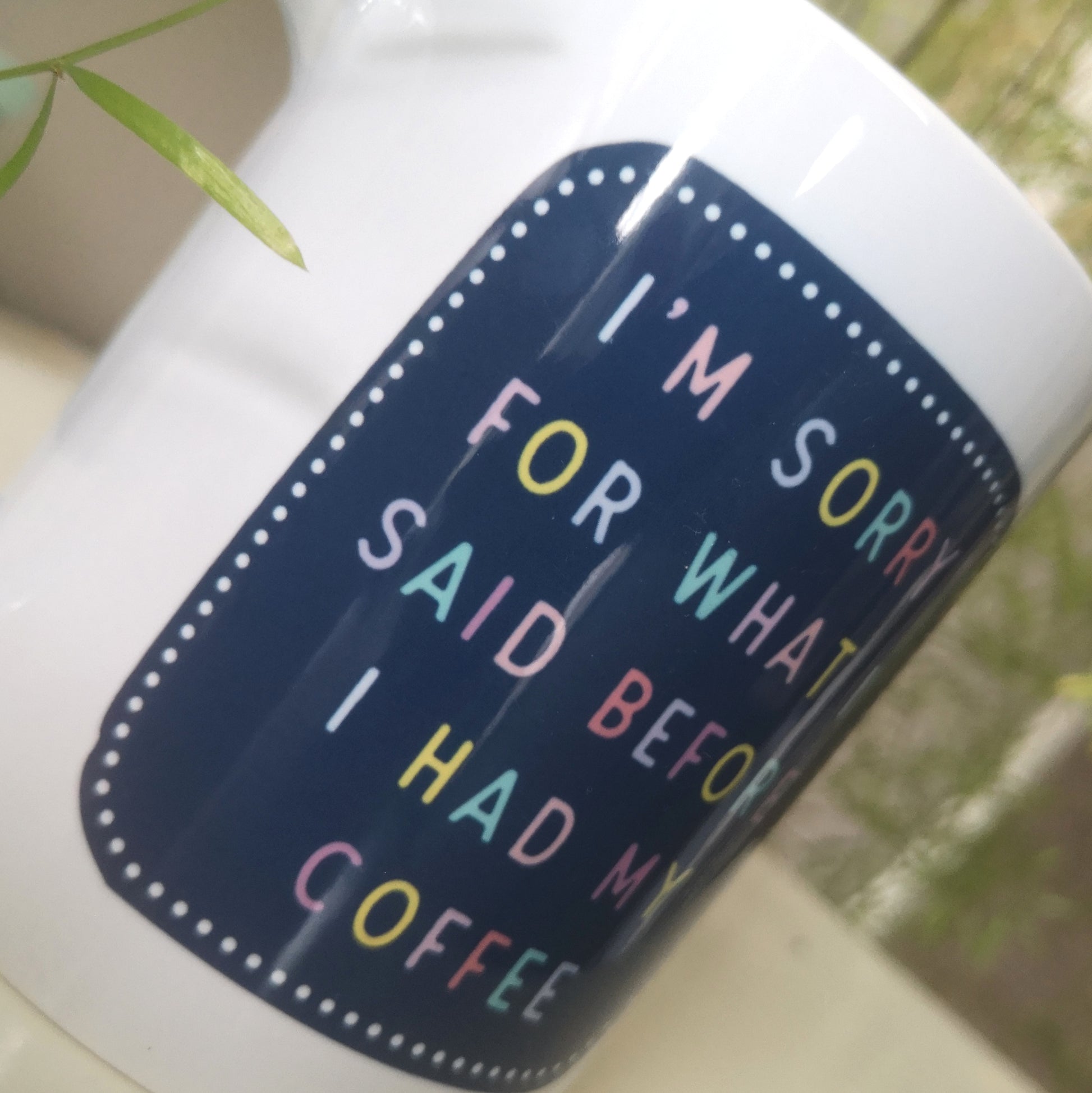A close up of a ceramic mug with 'I'M SORRY FOR WHAT I SAID BEFORE I HAD MY COFFEE' in colourful writing.