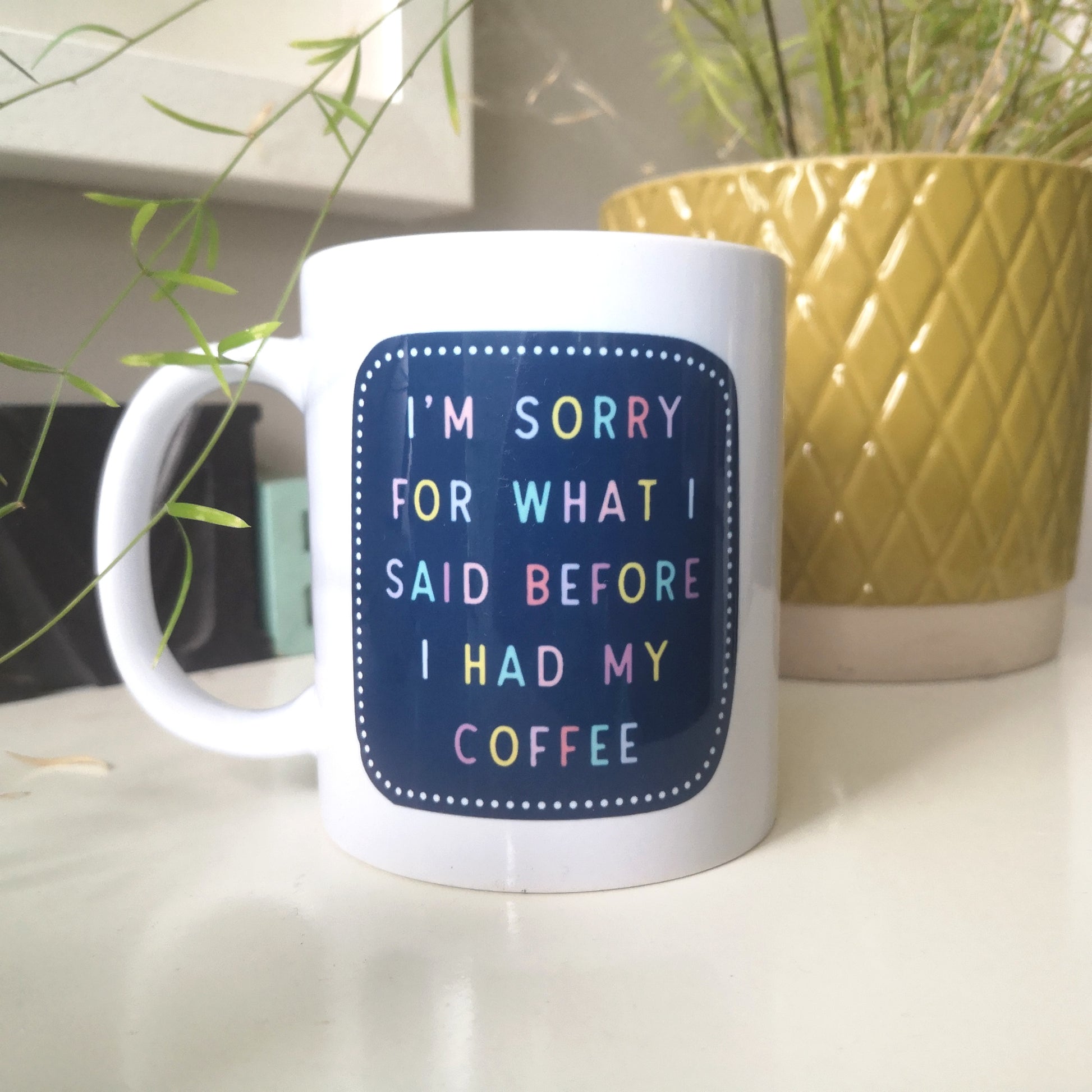 A ceramic mug with 'I'M SORRY FOR WHAT I SAID BEFORE I HAD MY COFFEE' in colourful writing.
