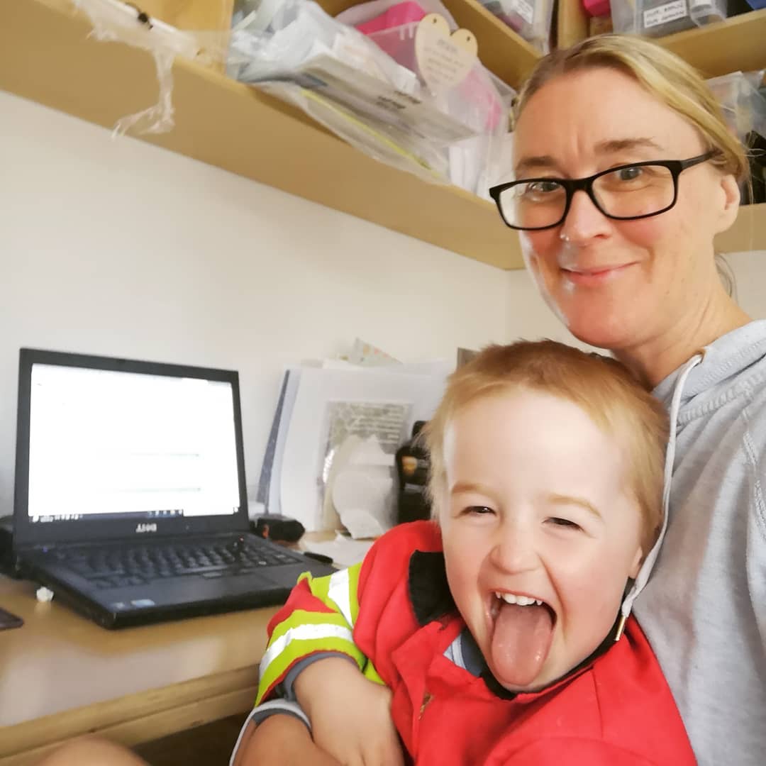 Loveletterarts Owner Aisling Scally and son sitting at her desk in workroom