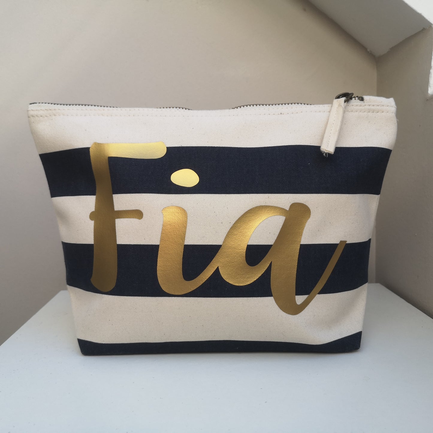 A navy and White personalised pouch with the name in gold textured font