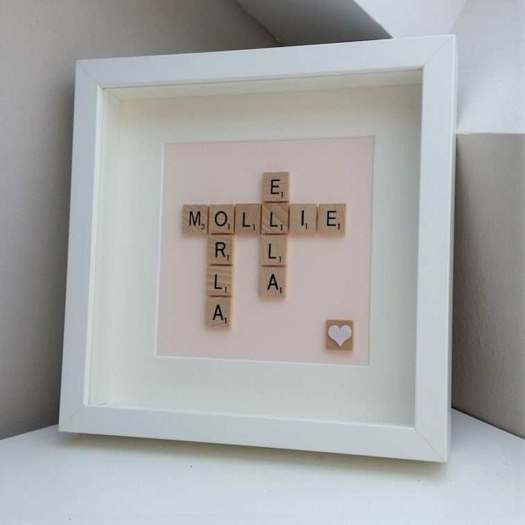 Personalised pink 3 name Scrabble frame on a pastel pink background and heart tile