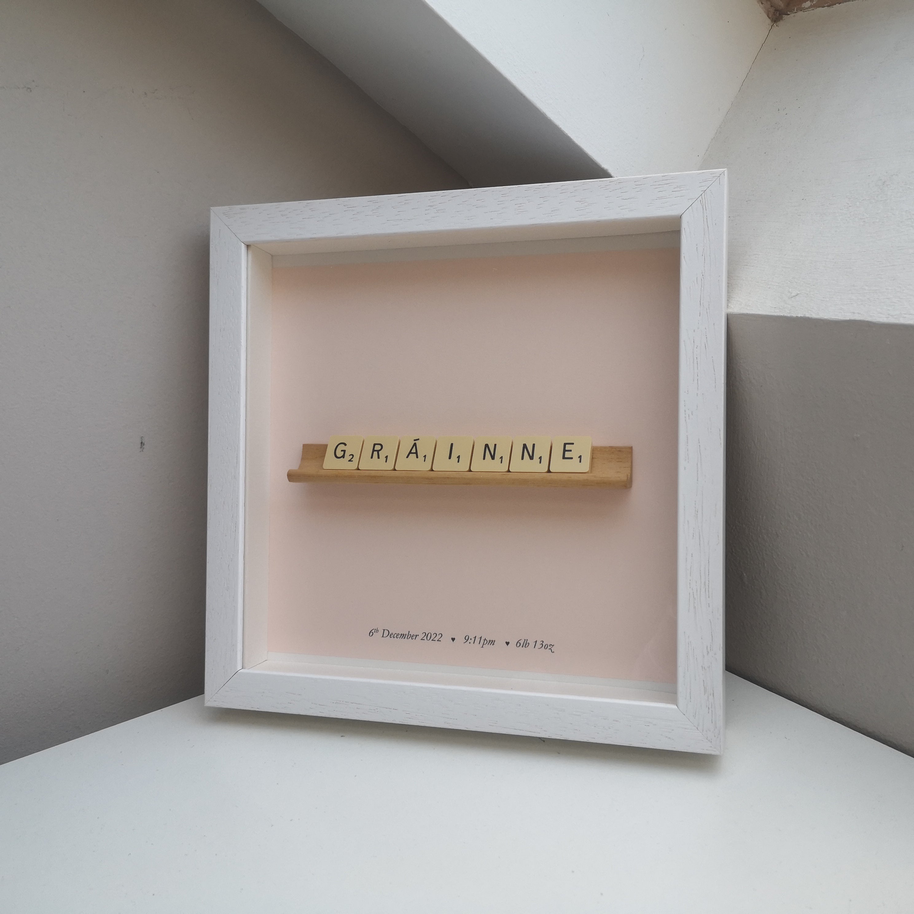 Scrabble Frame with girls name in vintage cream tiles on a vintage scrabble rack on pastel pink background