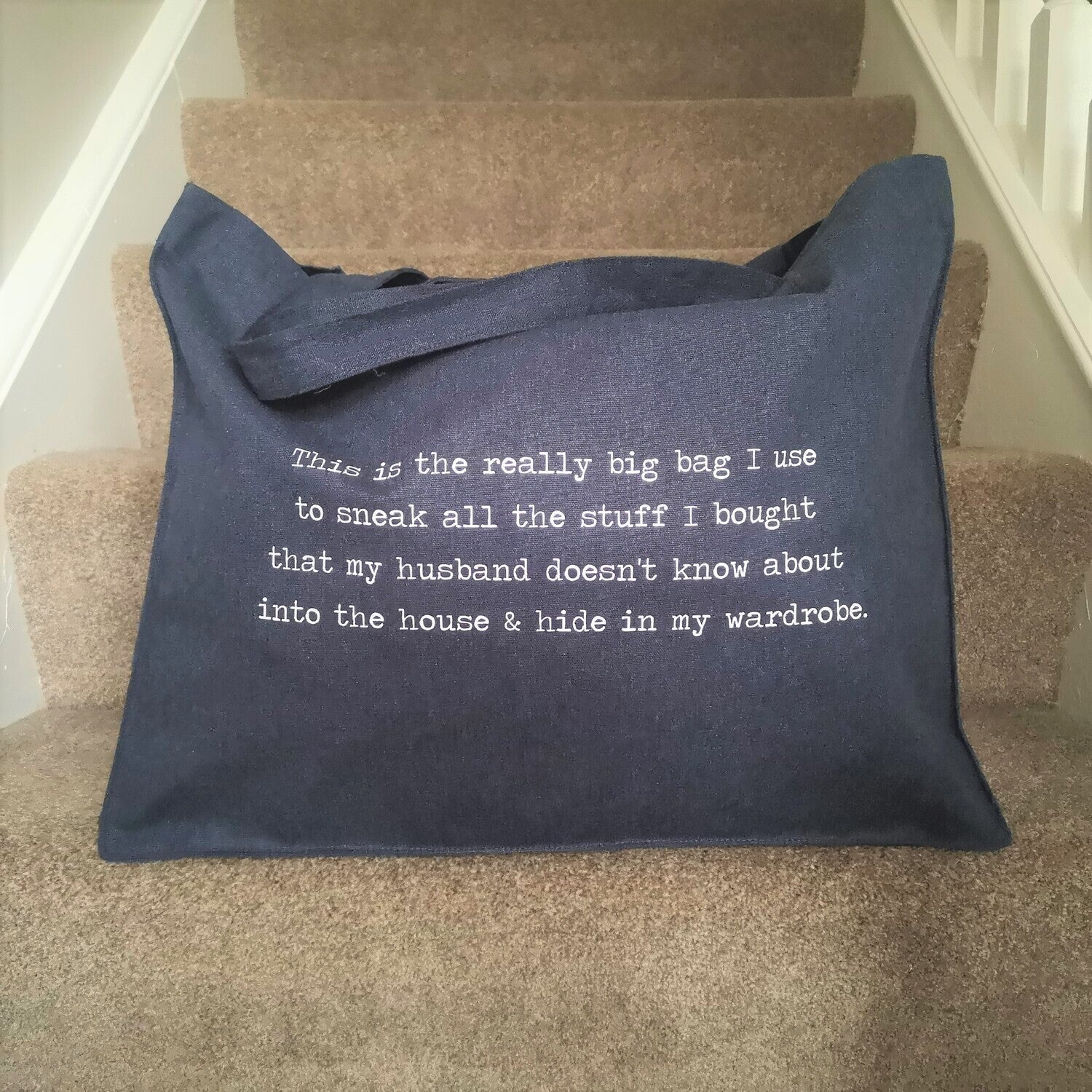 A large midnight blue organic cotton tote with the following text on it - This is the really big bag I use to sneak all the stuff I bought that my husband doesn't know about into the house & hide in my wardrobe.