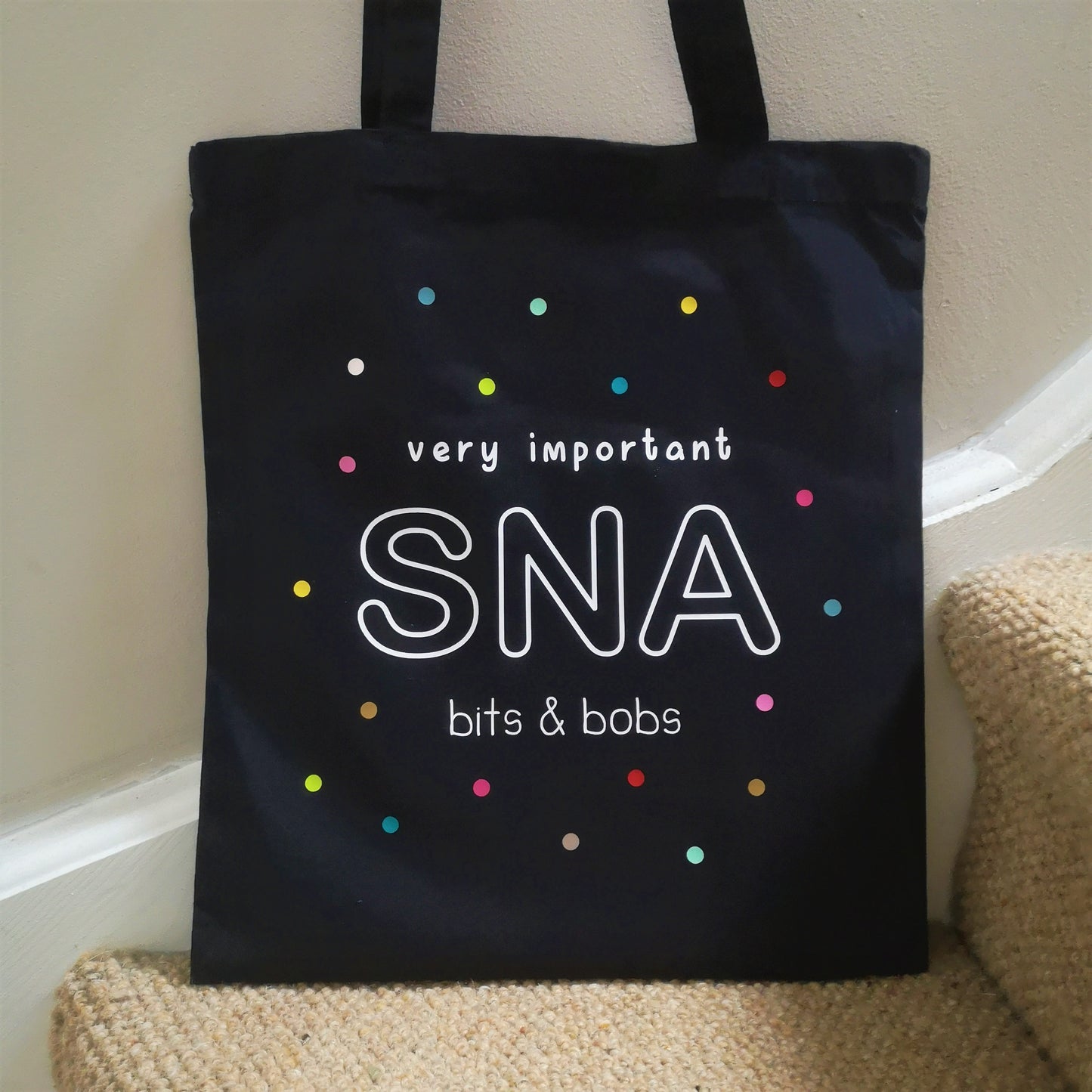 A personalised lightweight black cotton tote with VERY IMPORTANT SNA BITS & BOBS on it. The text is surrounded with multicoloured polkadots